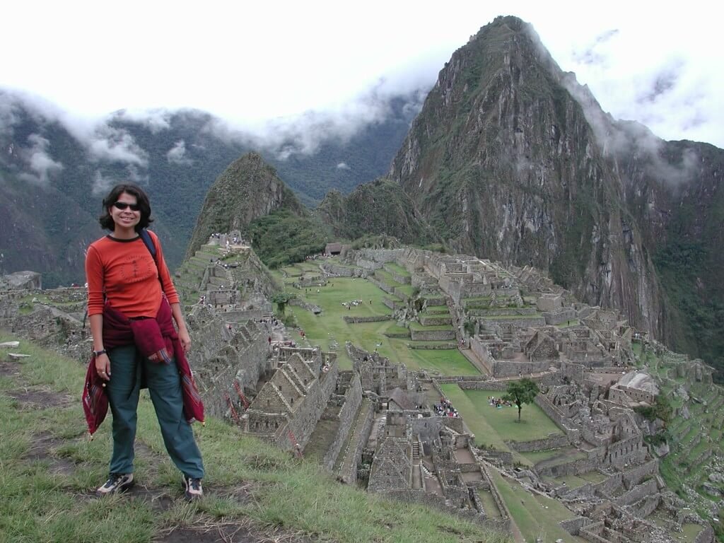 mulher com ruínas de Machu Picchu ao fundo