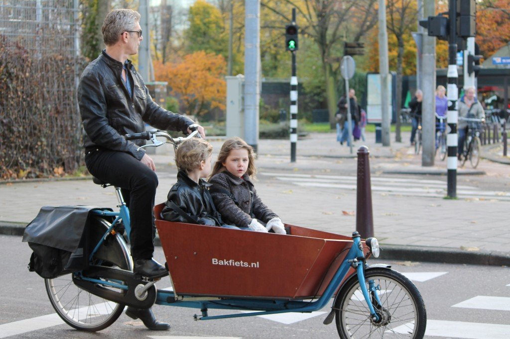 Pai andando com crianças de bicicleta em Amsterdam