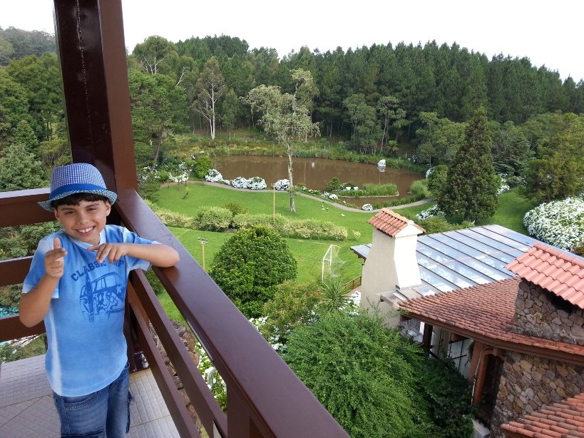 Criança rindo com área verde e lago