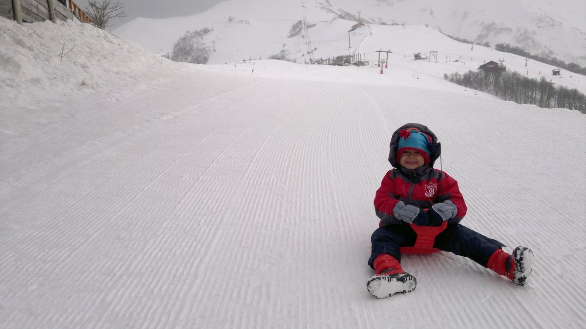 criança descendo neve de trenó